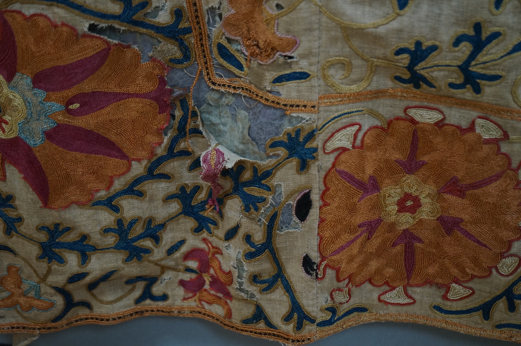 A 19th century, circa 1850-1880 hand embroidered Suzani wall hanging, probably from Uzbekistan. Worked on had woven linen, predominantly embroidered in orange, ochre, maroon and green silks in fine chain stitch with an o